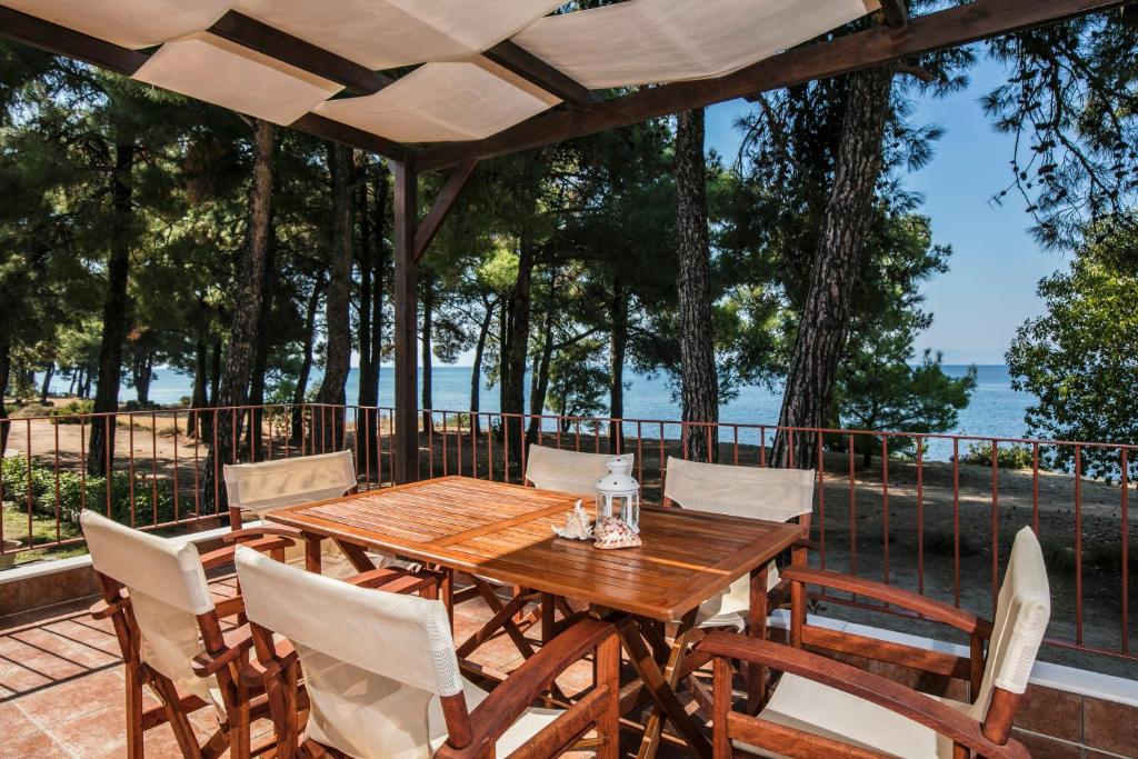 a wooden table and chairs on a deck with a view of the water at PineReef Blue in Skala Rachoniou