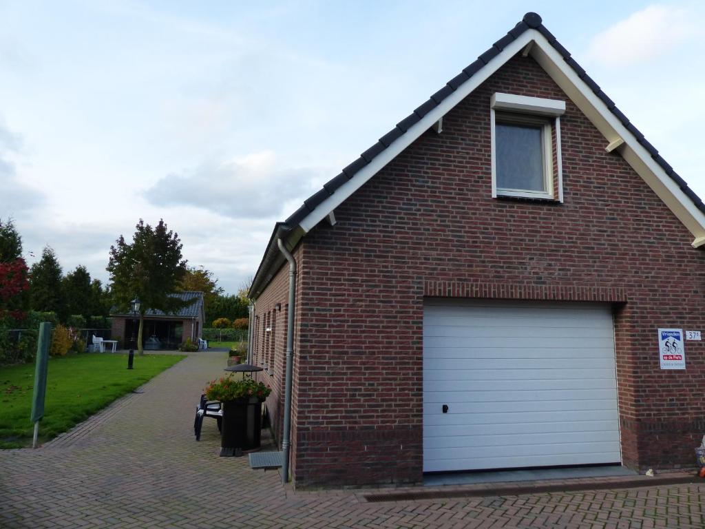 ein rotes Backsteinhaus mit einer weißen Garage in der Unterkunft De Zolder in Meterik