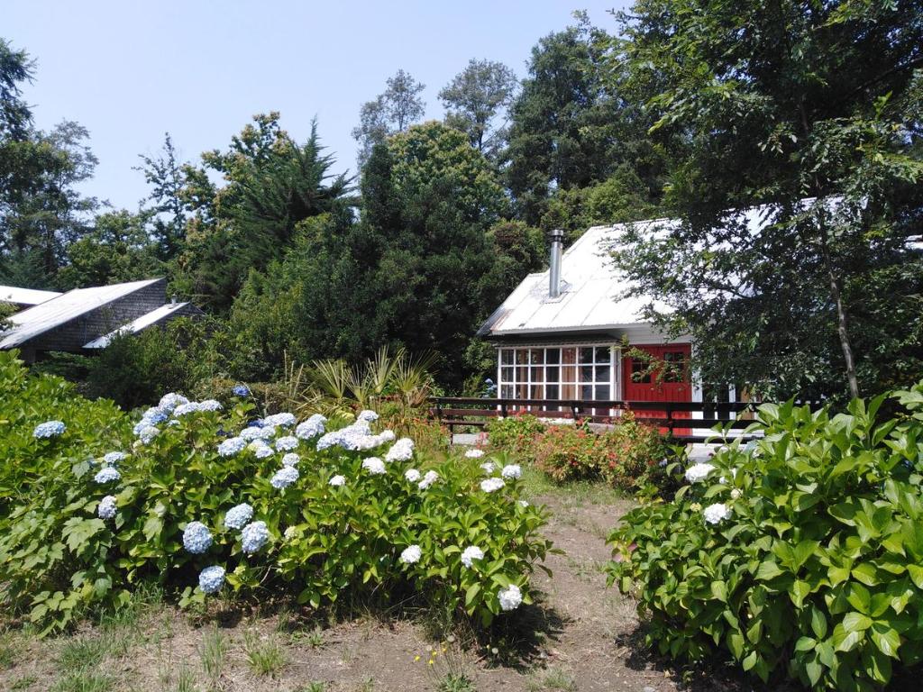 una casa con un jardín con flores delante en Cabañas Ruca Mahuida, en Pucón