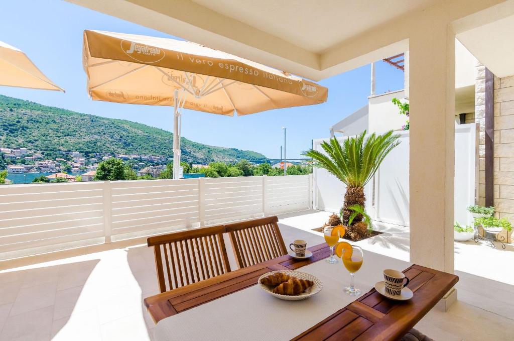 a table with two chairs and an umbrella on a balcony at Apartment Moon River in Mokošica