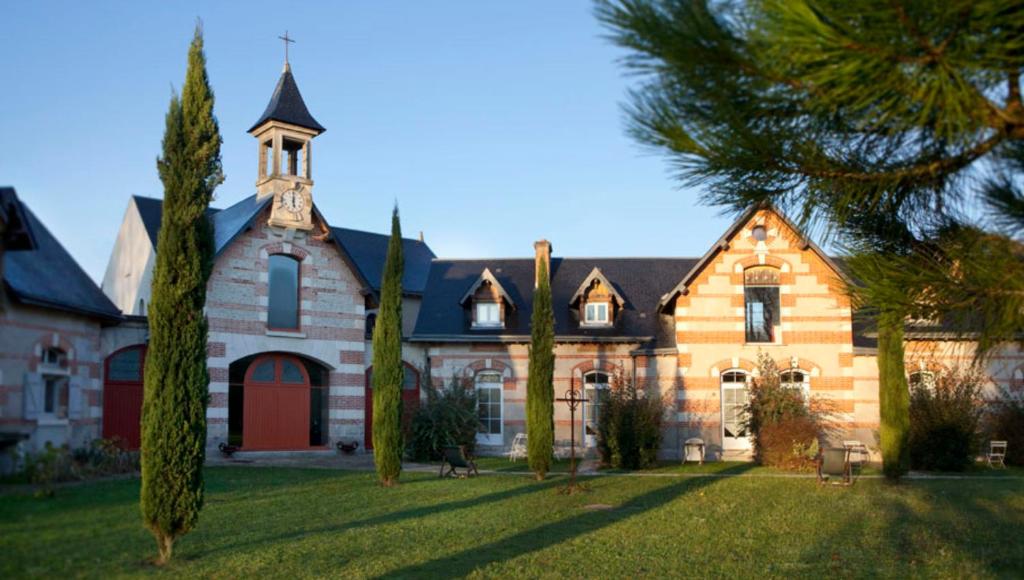 a large house with a church and palm trees at La Bretauche in Chécy