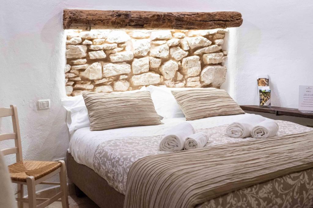 - une chambre avec un lit et un mur en pierre dans l'établissement Trullo Nobilis, à Alberobello