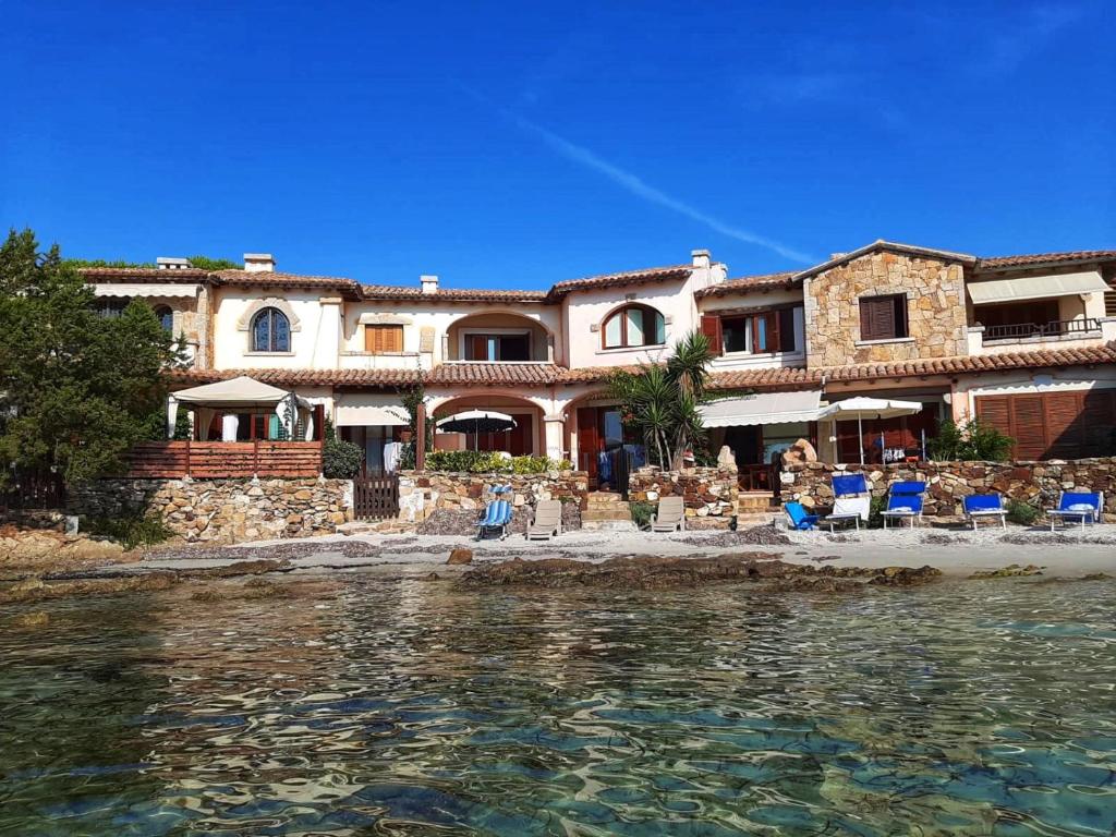 a large house on the beach with chairs and the water at Incanto Apartment Golfo Aranci in Golfo Aranci