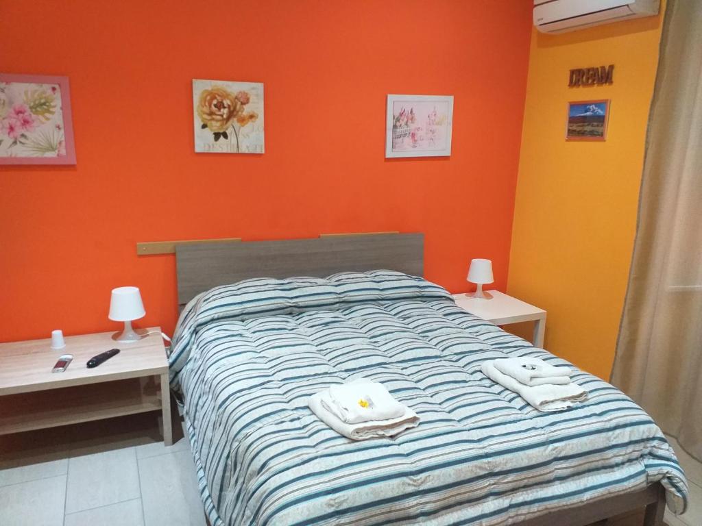 a bedroom with orange walls and a bed with towels on it at Bed Relax Etnaview Self check-in in Zafferana Etnea