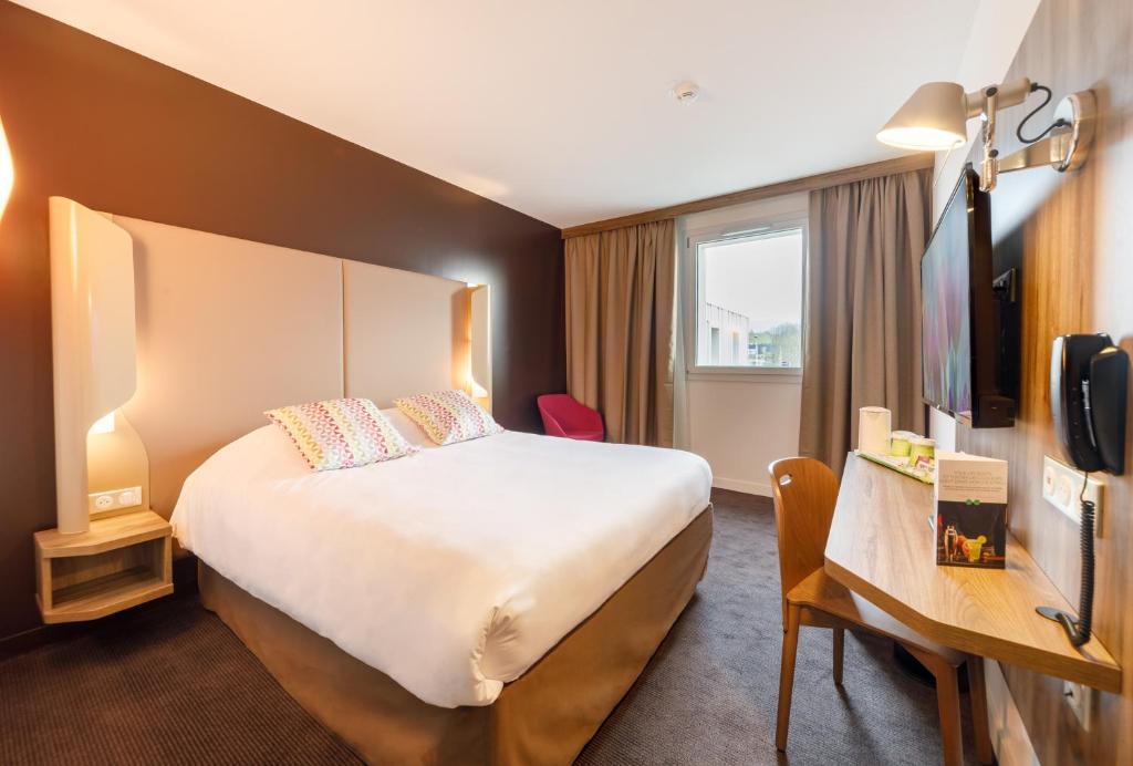 a hotel room with a large bed and a television at Campanile Findrol Annemasse Savoie Leman in Fillinges