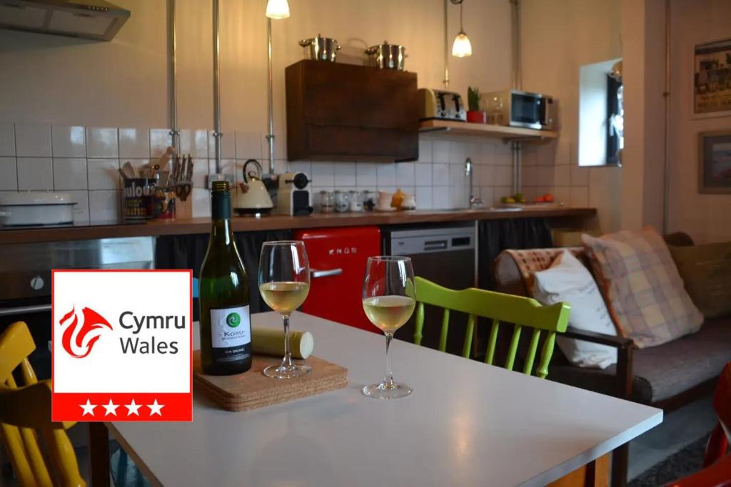 a bottle of wine and two glasses on a table at Cattle Shed Cottage in Narberth