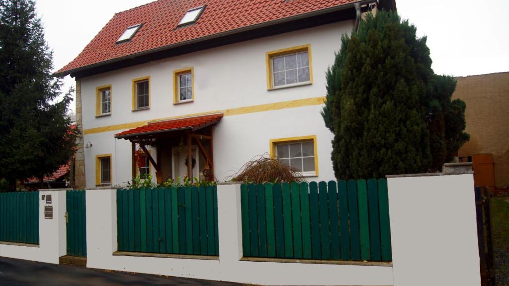 uma casa branca com uma cerca verde em Gästewohnung am Thümmlitzwald em Grimma