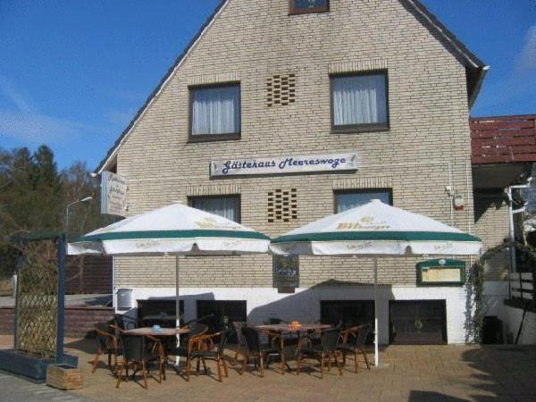 a patio area with a table, chairs, and umbrella at Hotel Meereswoge in Cuxhaven