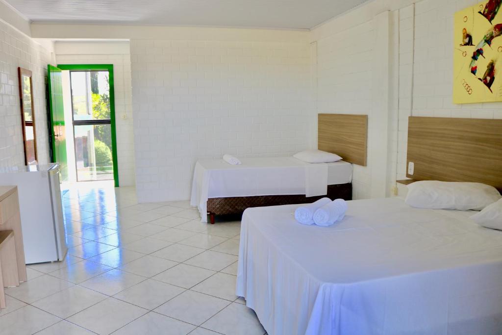 a white room with two beds and a window at Hotel e Parque das Tuias in Fontoura Xavier