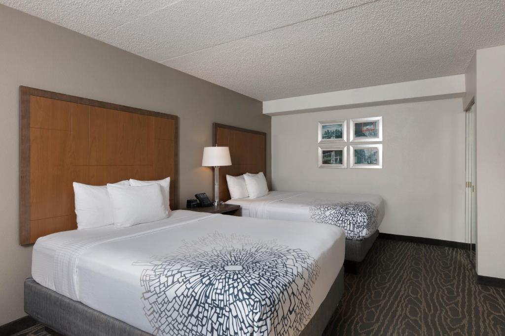 a hotel room with two beds and a lamp at La Quinta by Wyndham Secaucus Meadowlands in Secaucus