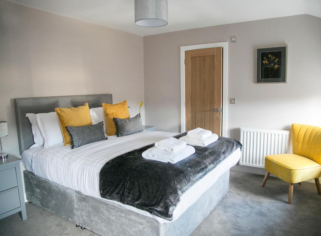 - une chambre avec un grand lit et une chaise jaune dans l'établissement Alpha Spa classic 1 bedroom apartment, à Harrogate