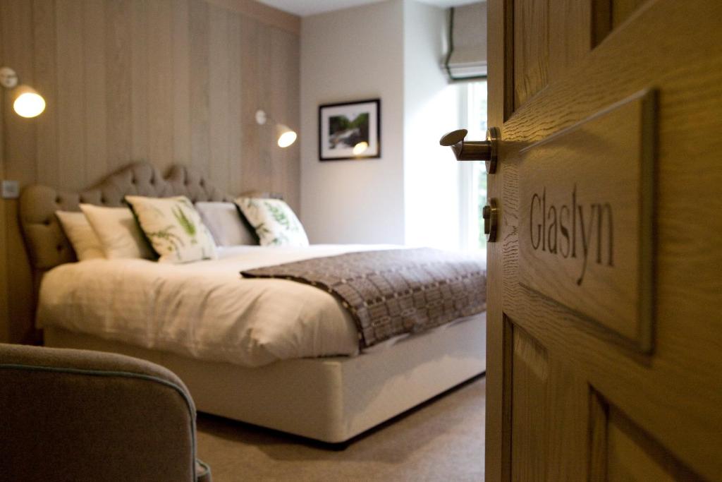 Un dormitorio con una cama con sábanas y almohadas blancas. en Saracens Head, en Beddgelert