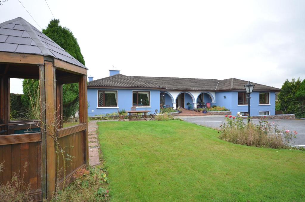 a blue house with a fence and a yard at Gormans Country Home in Killarney