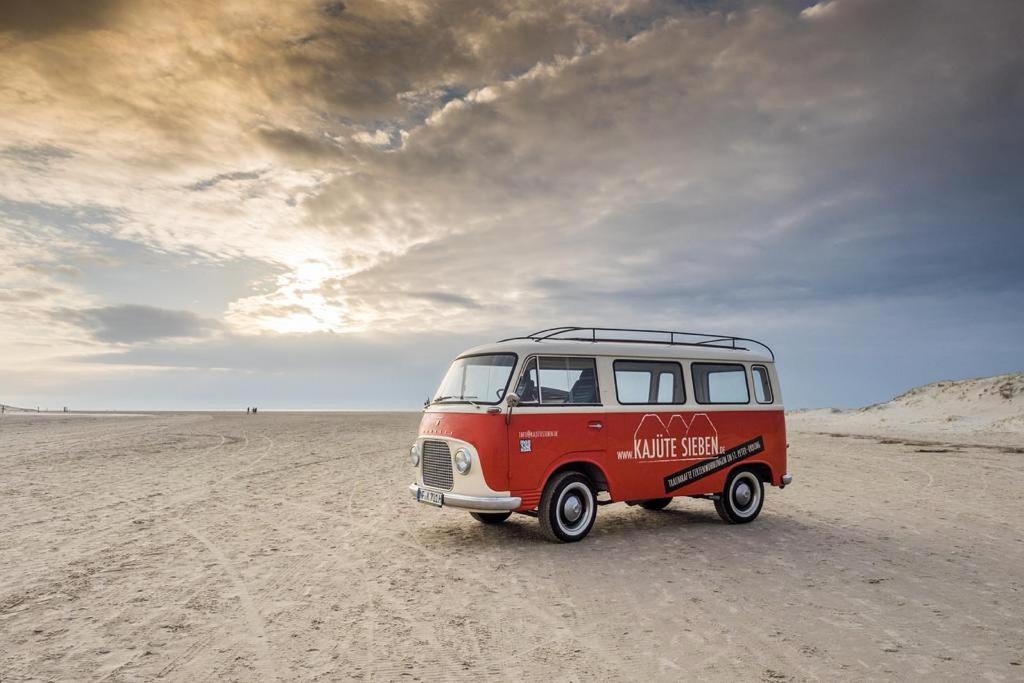 une vieille camionnette rouge garée dans le désert dans l'établissement KajüteSieben, à Sankt Peter-Ording