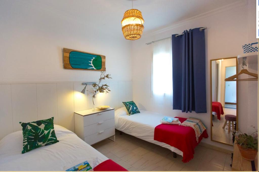 a bedroom with two beds and a mirror at Nexo Surf House in El Palmar