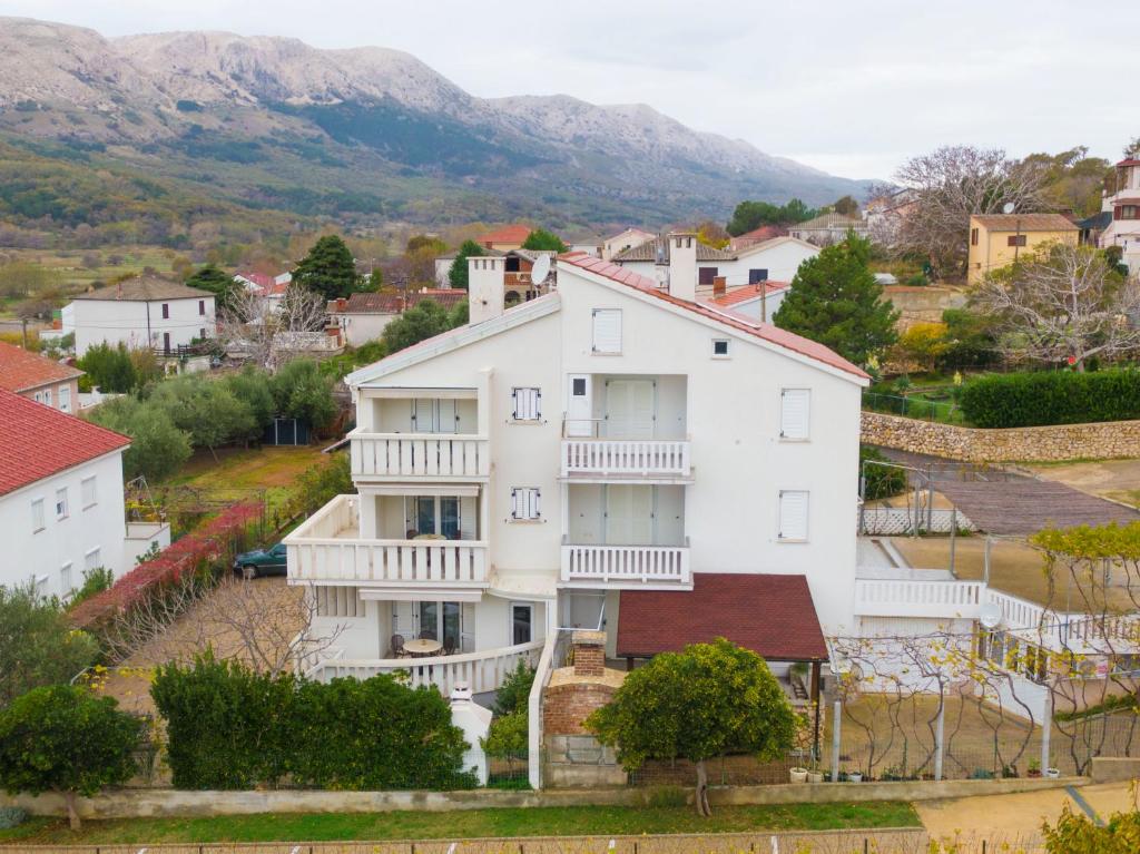 une grande maison blanche avec balcon et un village dans l'établissement Apartments IDa II, à Baška