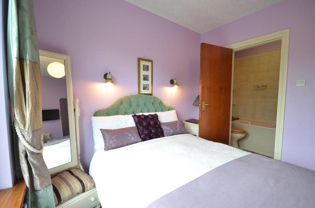 a purple bedroom with a bed and a mirror at Gormans Country Home in Killarney