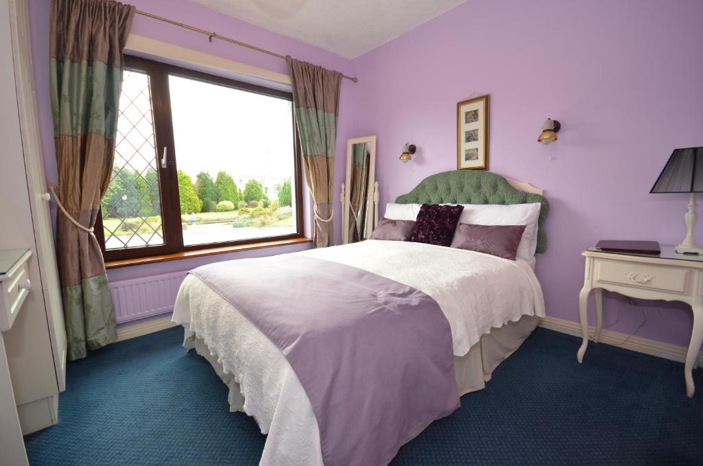 a purple bedroom with a large bed and a window at Gormans Country Home in Killarney