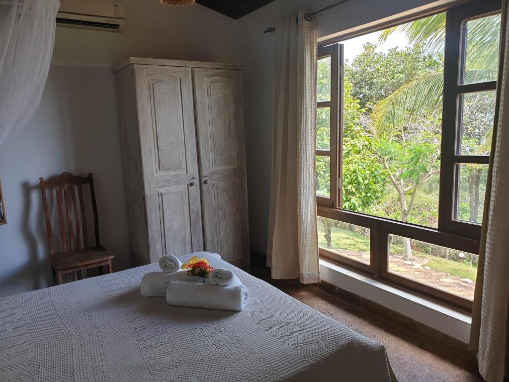 琵琶的住宿－Chalé Colibri Vista Mar Condominio Varandas de Pipa，一间卧室配有带毛巾的床和窗户。