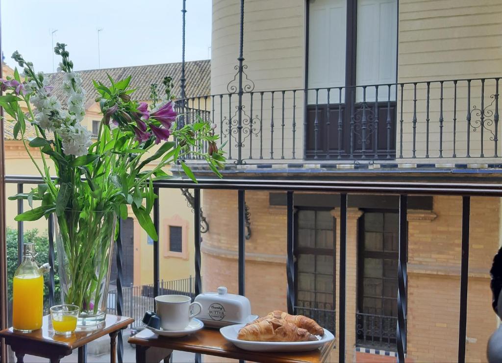 a table with a plate of food and a vase of flowers at Ispal Apartment & Parking Seville Historic Center vutse06601 in Seville