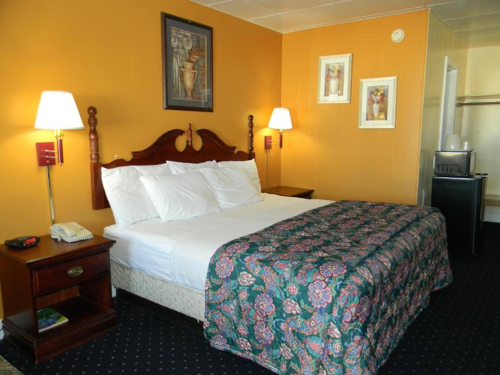 a hotel room with a large bed and two lamps at Fairfax Motel in Roanoke Rapids