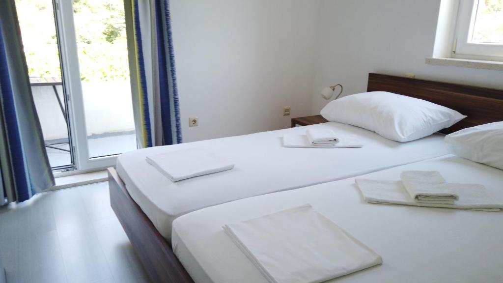 two white beds in a room with a window at Guest House Kukuljica 2 in Zaton