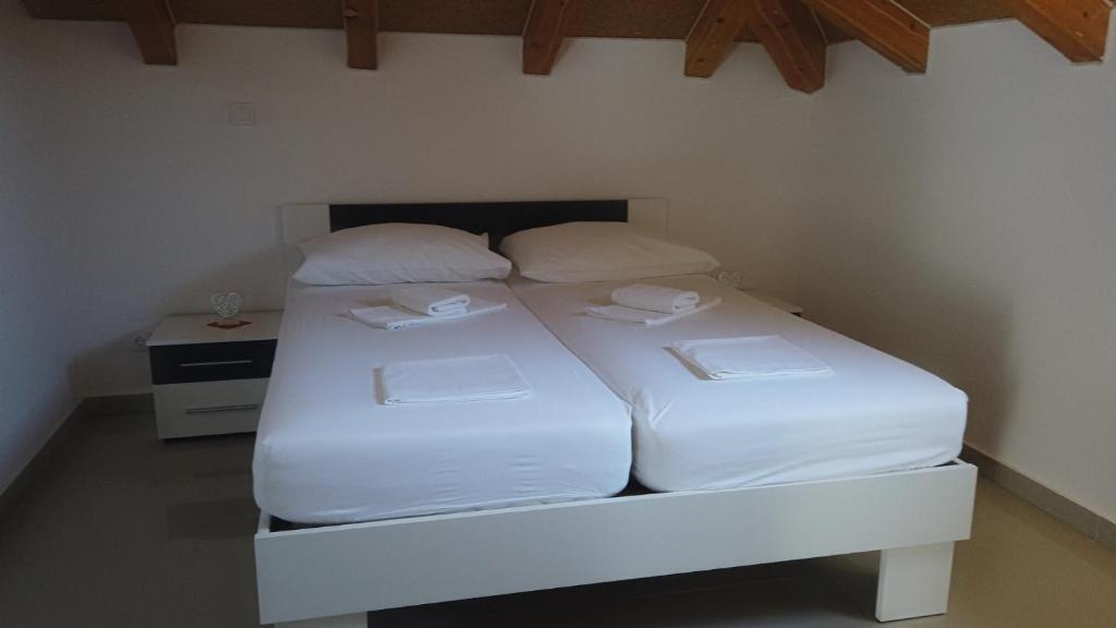 a white bed with two pillows on it in a room at Guest House Kukuljica 2 in Zaton