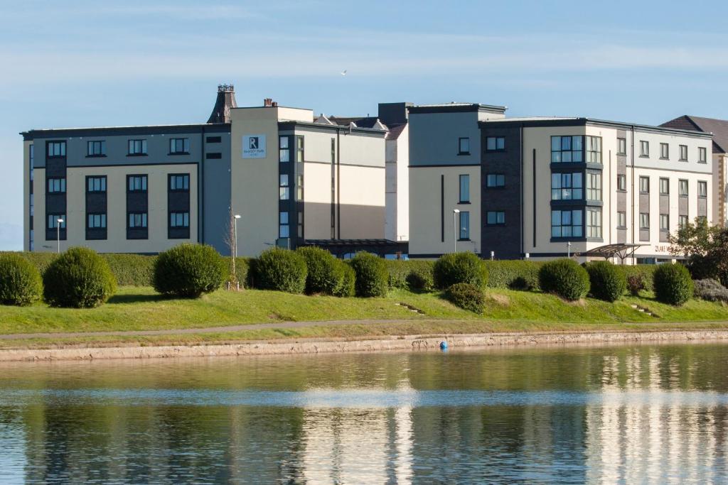 eine Reihe von Gebäuden neben einem Wasserkörper in der Unterkunft Ramsey Park Hotel in Ramsey