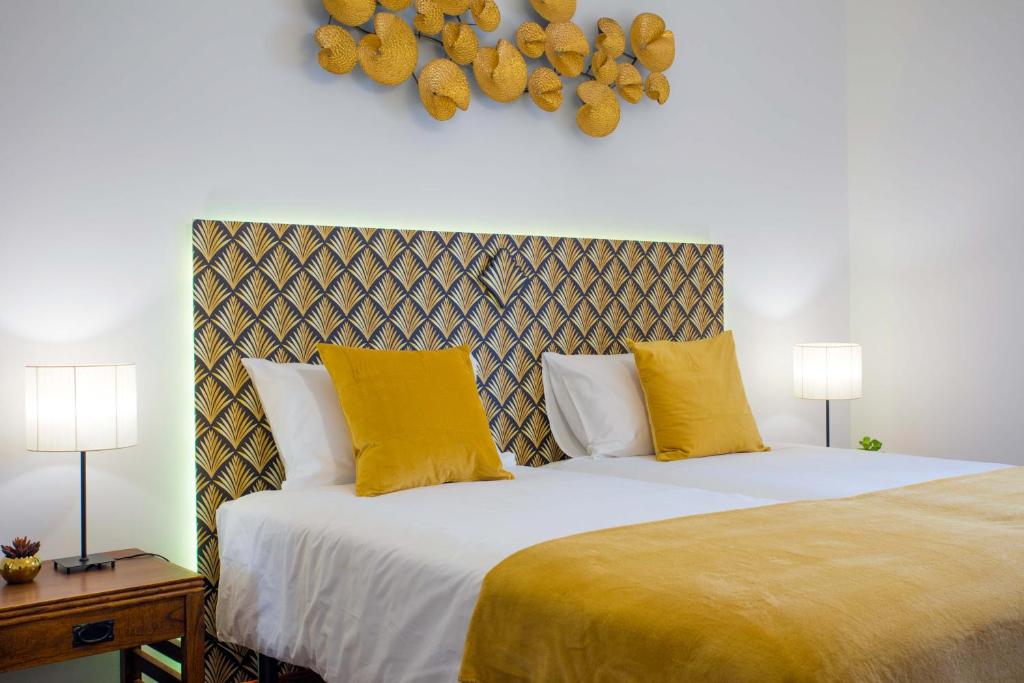 a bedroom with a bed with two yellow pillows at Casa Bom Dia in Sintra