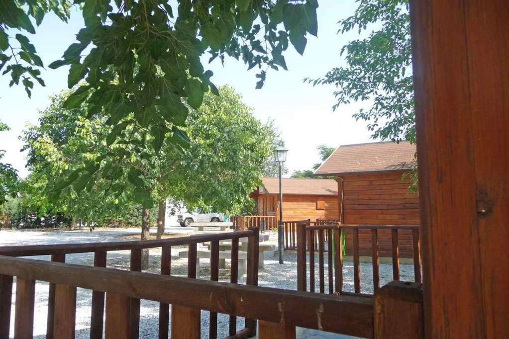 un porche de madera con una valla de madera y un edificio en Cabañas Negratín, en Cuevas del Campo