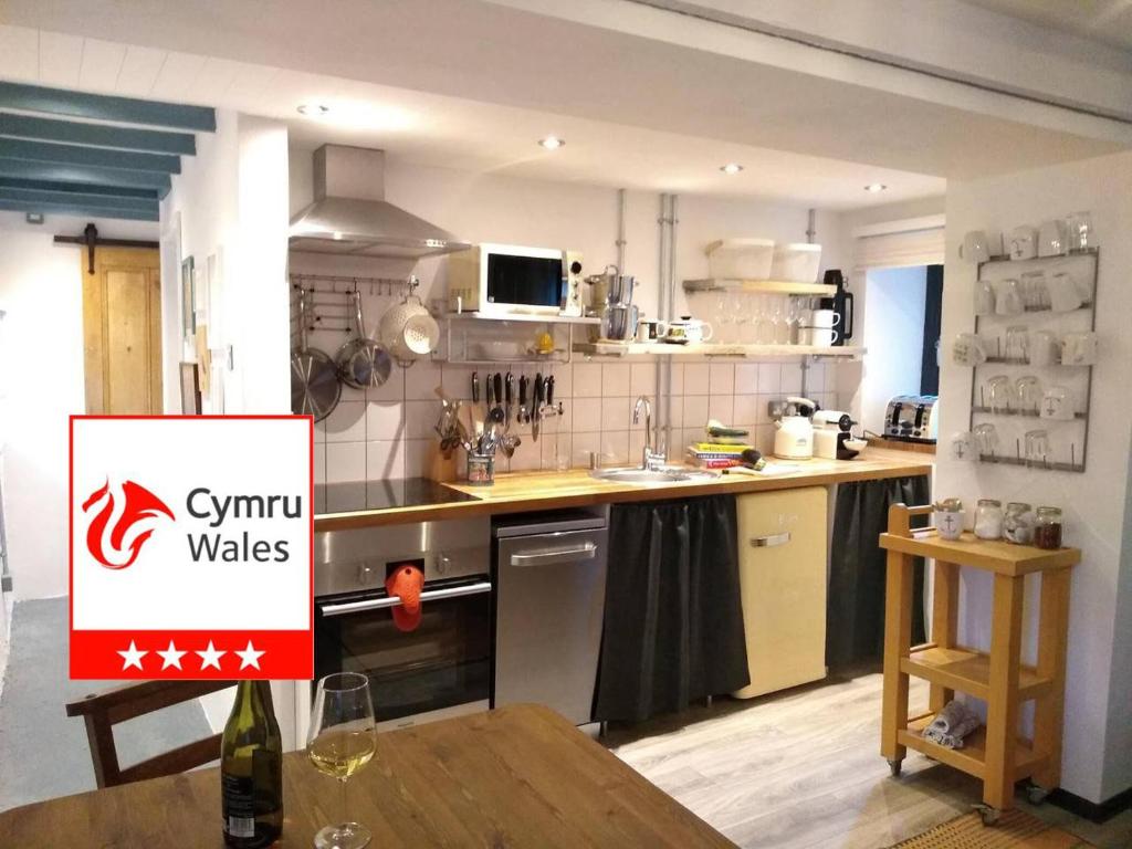 a kitchen with a table and a sign in it at Farmhand Cottage in Narberth