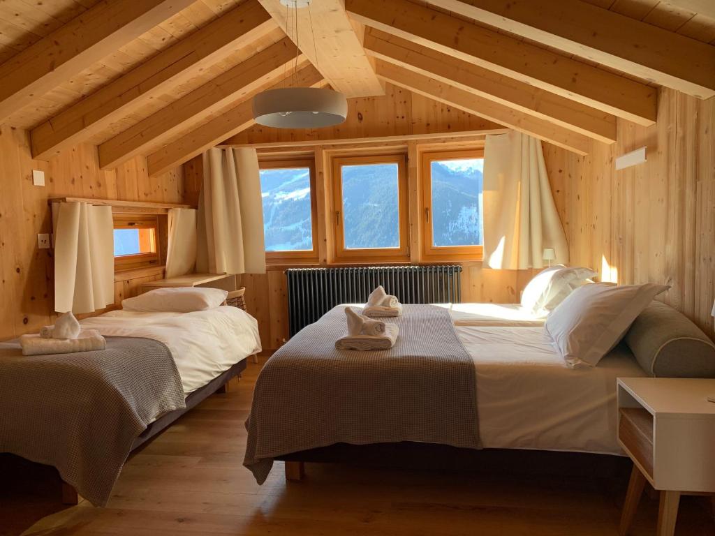 two beds in a room with wooden ceilings and windows at Hotelski in Verbier