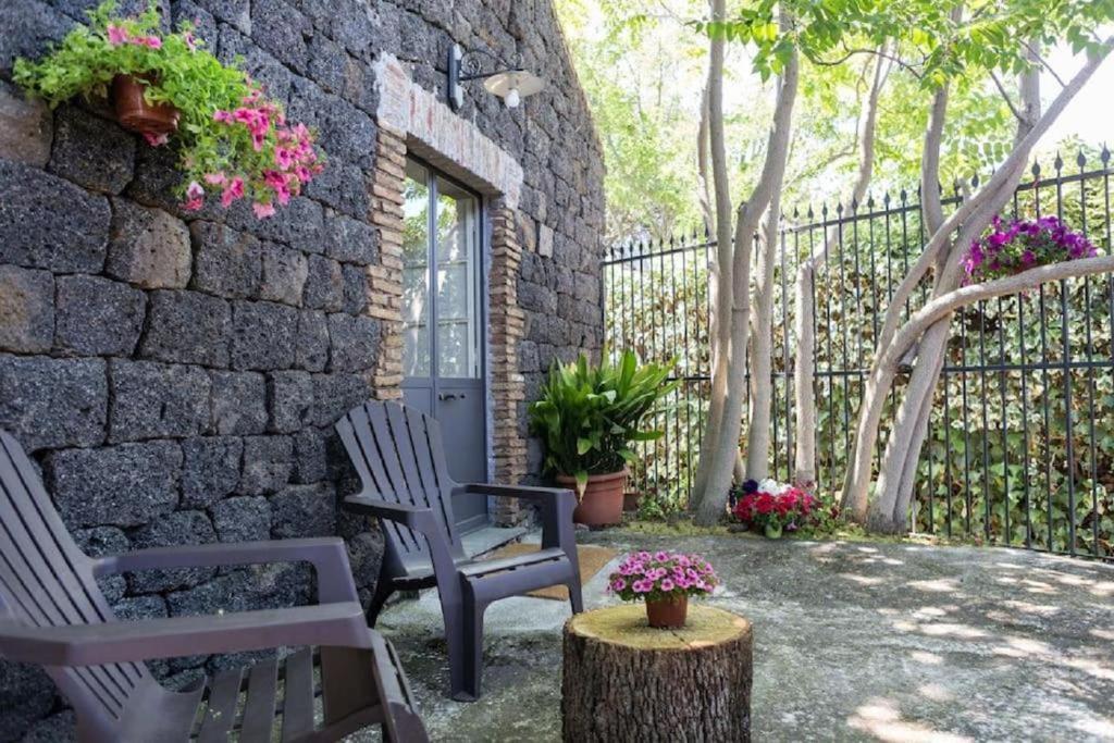 patio z 2 krzesłami i kamienną ścianą w obiekcie Pietra dell'Etna w mieście Ragalna