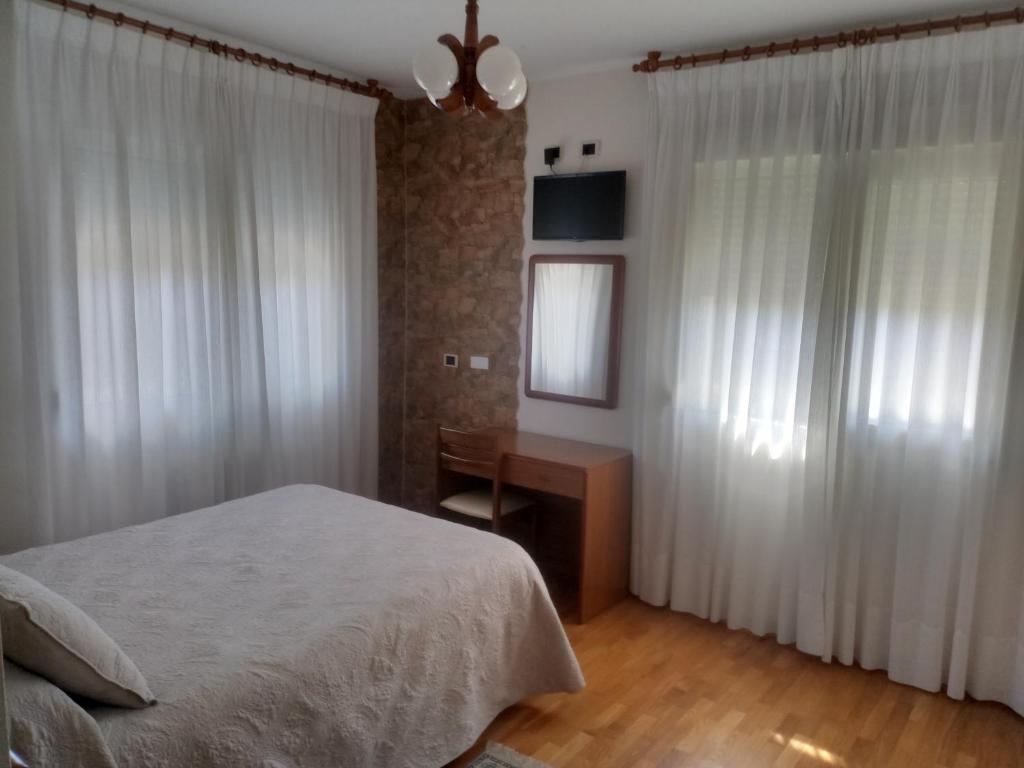 a bedroom with a bed and a desk and curtains at Hotel Arume in Bóveda