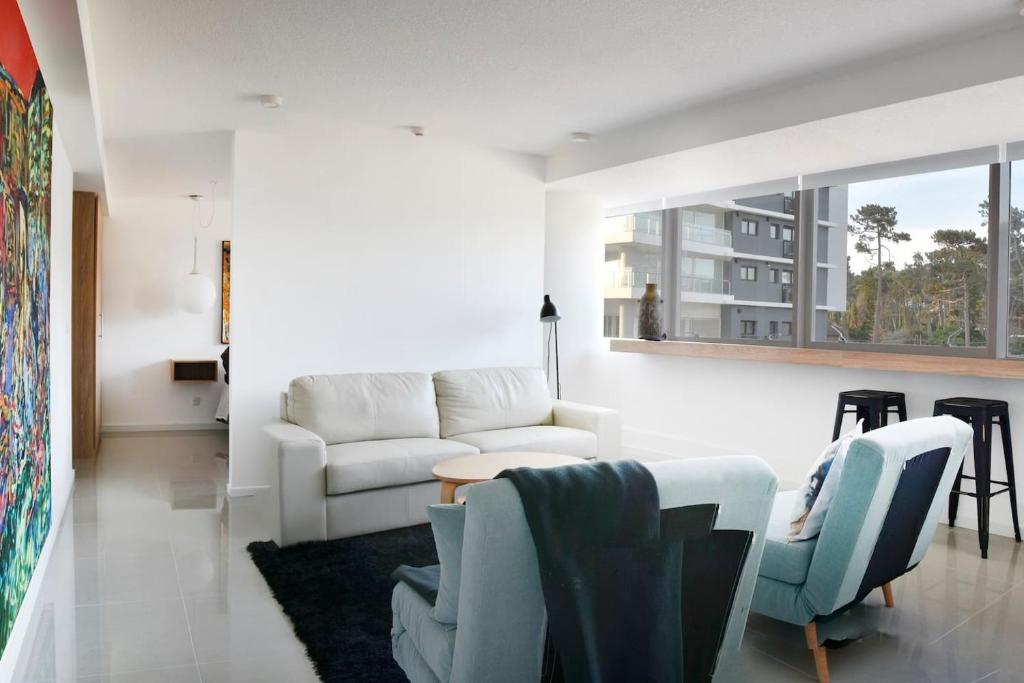 sala de estar con sofá blanco y sillas en Moderno apartamento en Edificio One Torre 2, en Punta del Este