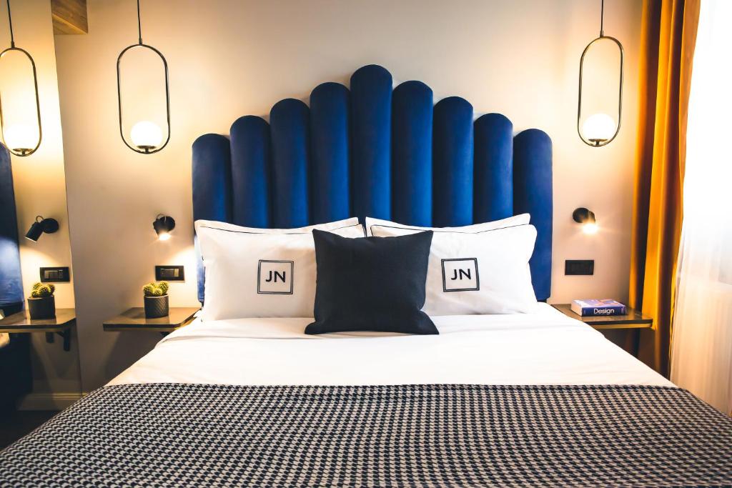a large bed with a blue headboard and pillows at JN Boutique House in Bucharest