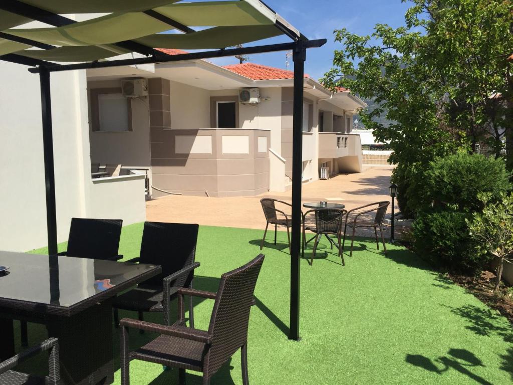 a patio with a table and chairs on grass at DeniaStella villas in Skala Potamias