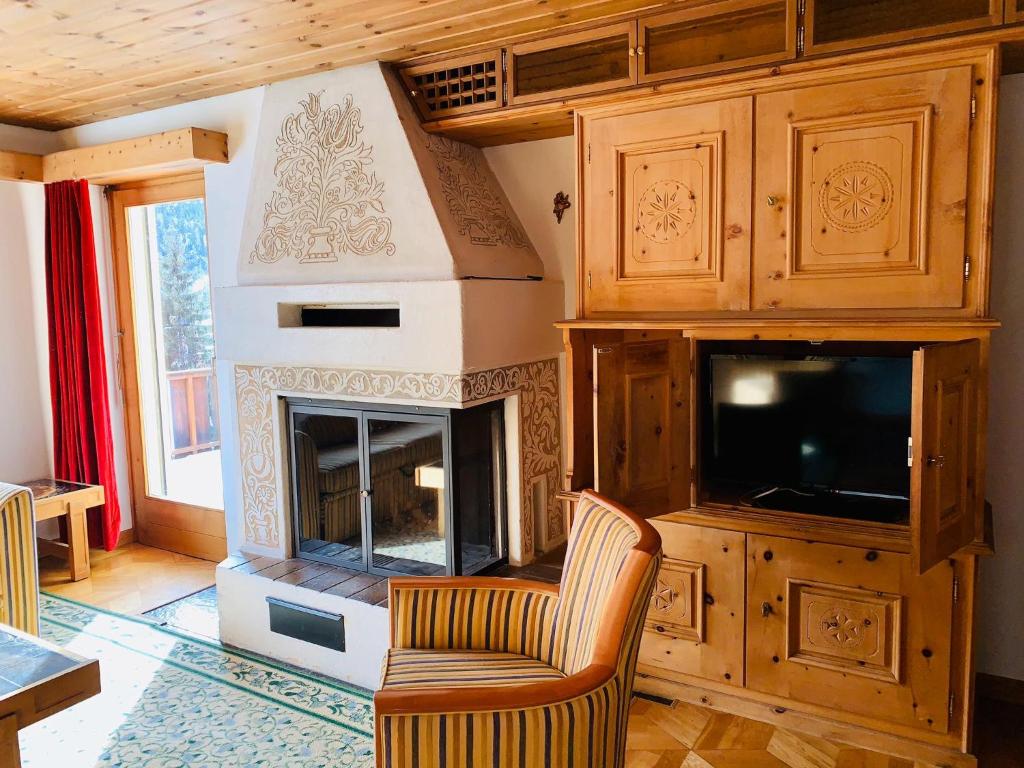 a living room with a fireplace and a television at Hotel Scuol in Scuol