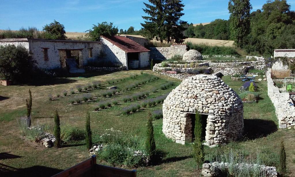 un jardin avec une maison en pierre dans un champ dans l'établissement Les Bories en Champagne, à Montlevon