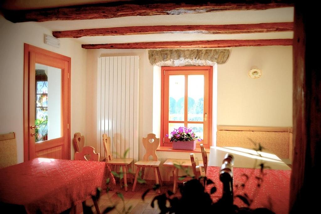 ein Esszimmer mit einem Tisch, Stühlen und einem Fenster in der Unterkunft Agriturismo Plan Da Crosc in Prato Carnico
