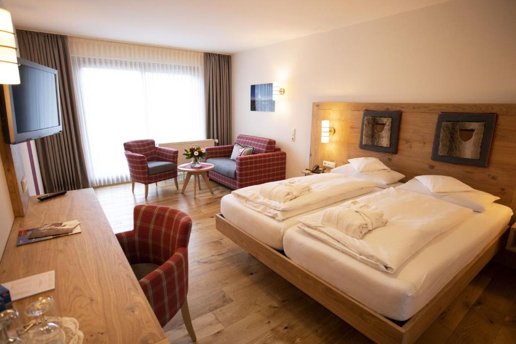 ヴィリンゲンにあるWellnesshotel Bürgerstubenの大きなベッドとリビングルームが備わるホテルルームです。