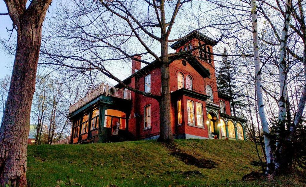 una gran casa de ladrillo rojo en la cima de una colina en Île de Garde B&B, en Sherbrooke