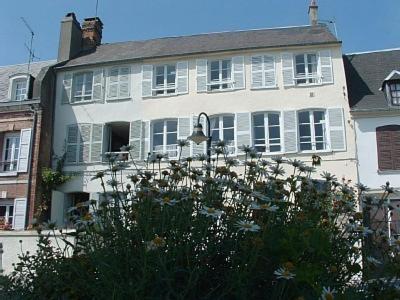une maison blanche avec des fenêtres blanches et des fleurs devant elle dans l'établissement Quai Peree Apartement, à Saint-Valery-sur-Somme
