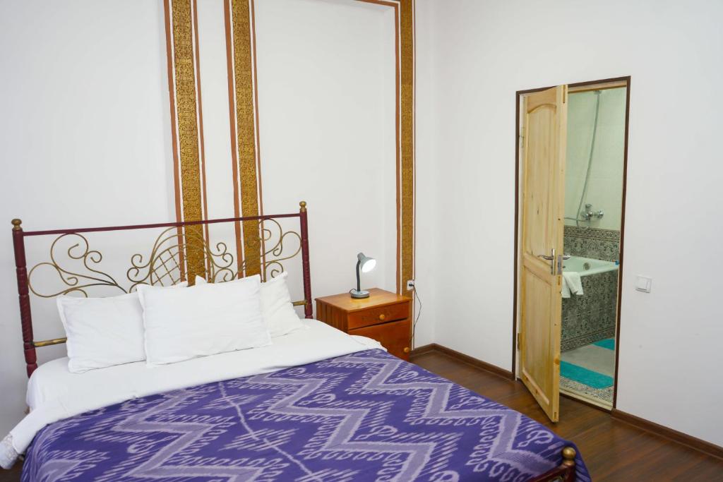 a bedroom with a bed and a mirror and a bathroom at B-House Hotel in Bukhara