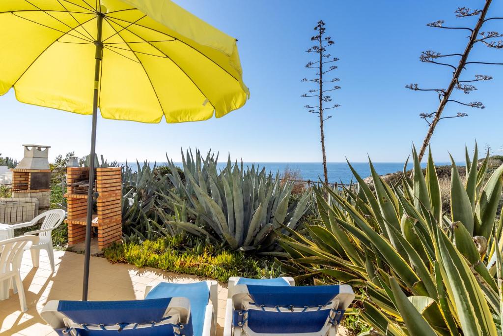 a patio with chairs and an umbrella and the ocean at Apartment Isabel in Carvoeiro