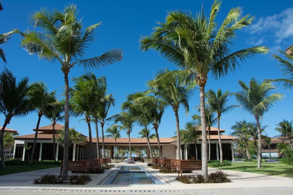 a row of palm trees in front of a building at Mandara Lanai in Aquiraz