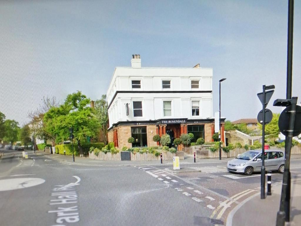 a white house with a car parked in front of a street at Home from Home, Great Community!! in London