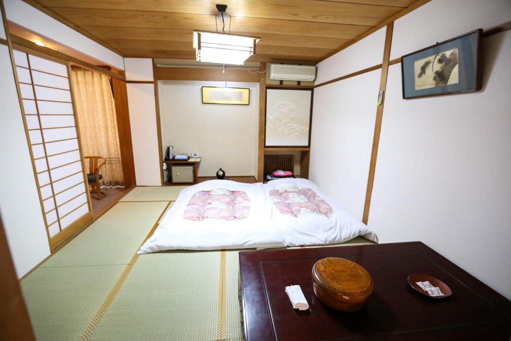 mały pokój z łóżkiem i stołem w obiekcie 楽奇温泉旅館 w mieście Yamanouchi