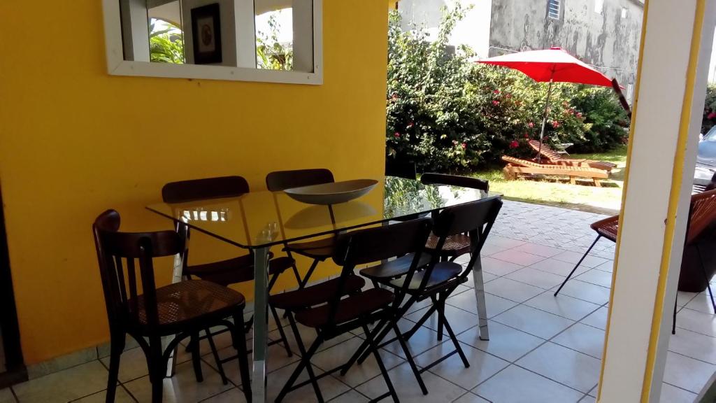 a dining room table with chairs and an umbrella at Maison CÉCILIA in Port-Louis