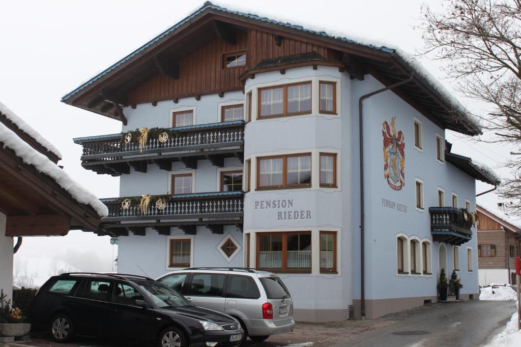 a building with two cars parked in front of it at Pension Rieder in Leogang
